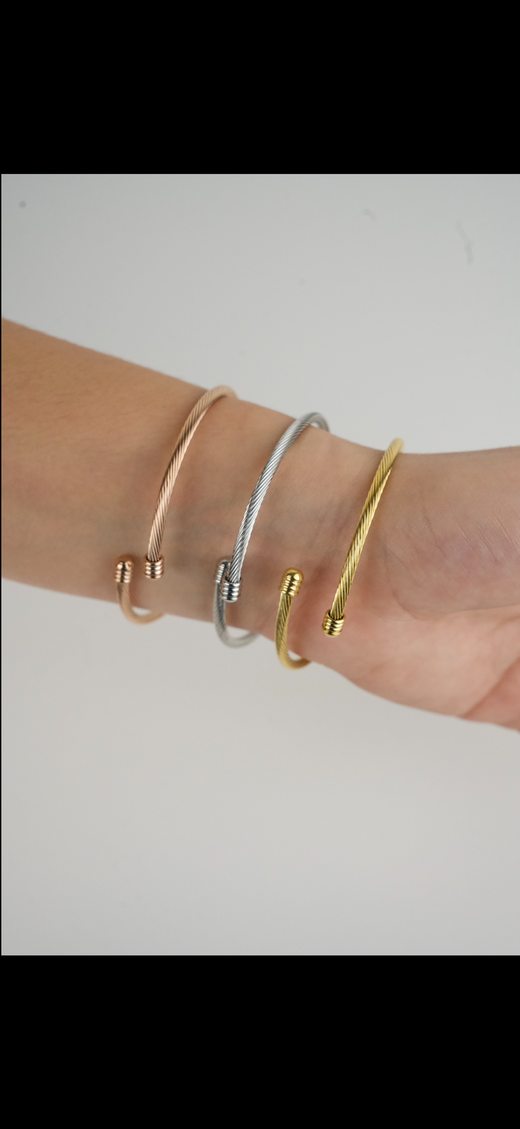 These are Charriol-style cable wire cuff bangles in silver, rose gold, and gold-tone stainless steel with a knot design.